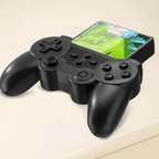 A black game controller with a built-in screen on top, resting on a light beige surface.
